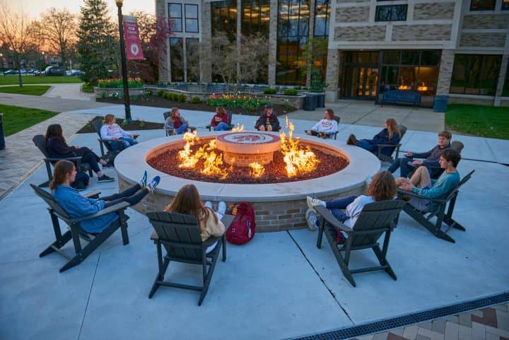 walsh university students gathered around a fire pit on campus