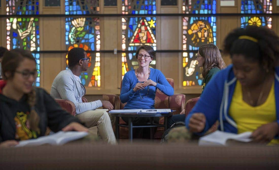 St. Norbert College theology professor teaching students in front of stained glass