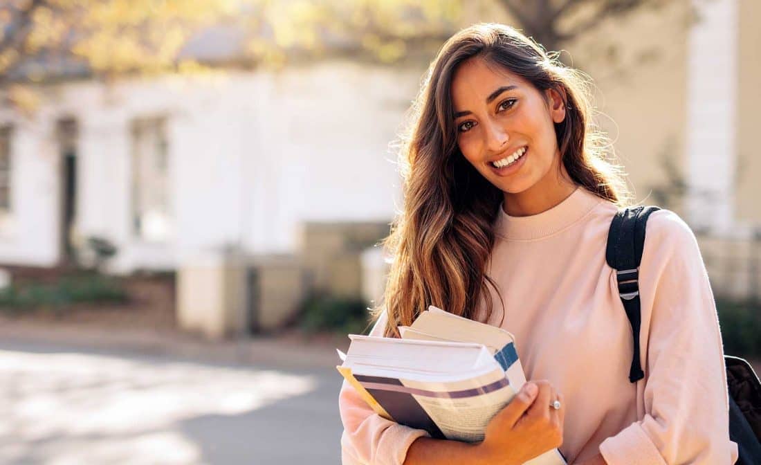 female student holding books on campus