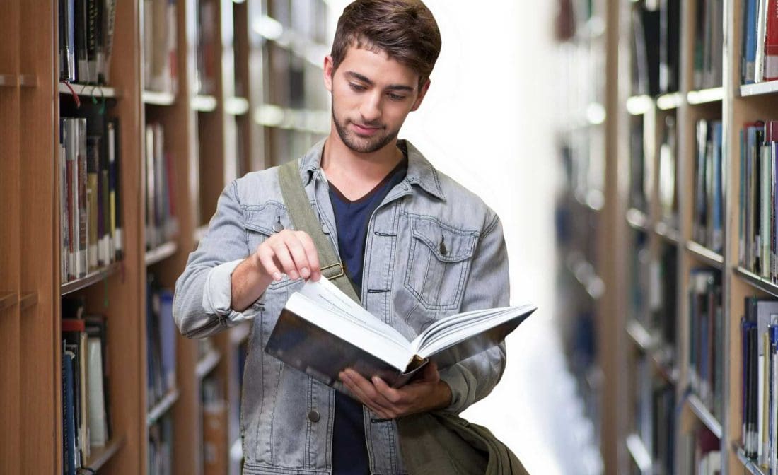 man in library looking at book