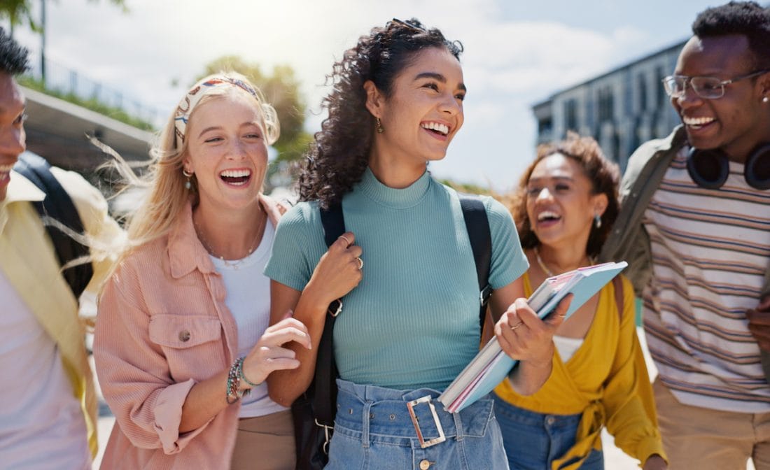Group of smiling high school seniors walking together on a college campus, representing full ride scholarship success and college opportunity