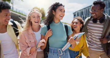 Group of smiling high school seniors walking together on a college campus, representing full ride scholarship success and college opportunity